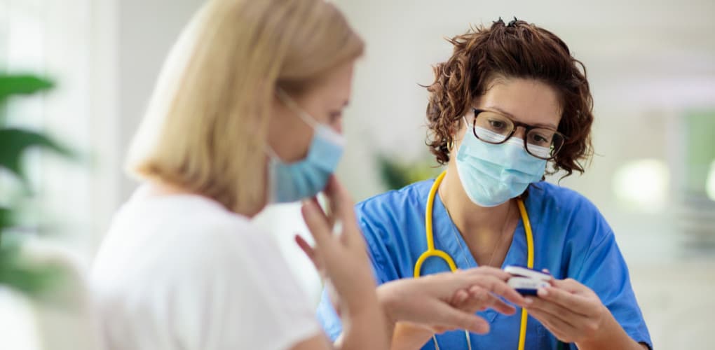 Woman with brown hair and blue scrubs is working with a patient