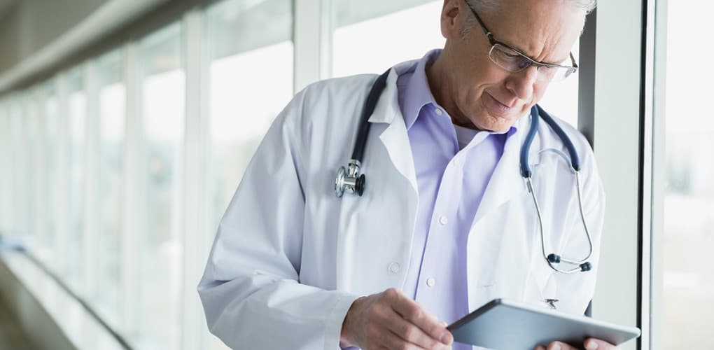 physician wearing white coat looking at tablet