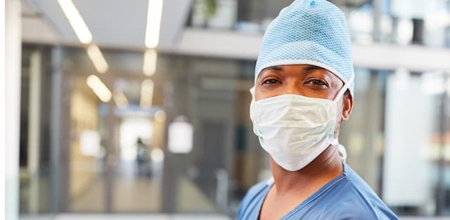 image of physician wearing a mask and cap in front of surgical facilities