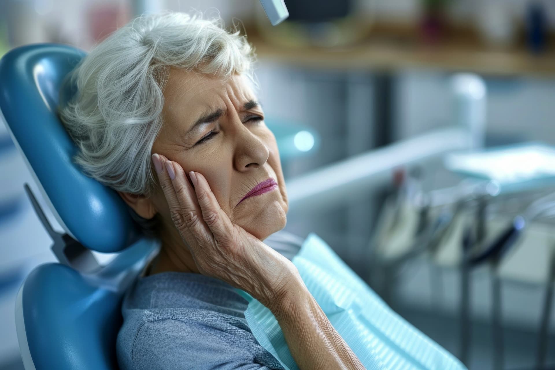 elderly female touches her jaw in pain