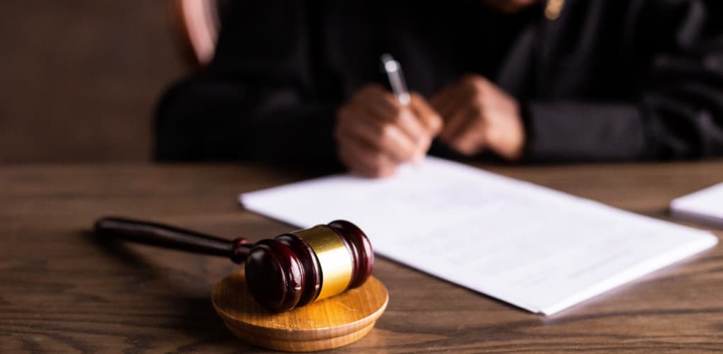 judge writing on a document next to a gavel